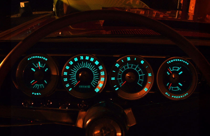 Car dashboard illuminated at night, featuring an electroluminescent panel displaying various controls and indicators
