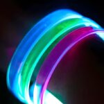 Close up image of clear LED bracelets when turned on, blue, green, and pink LED bracelets on wrist