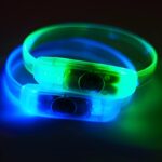 Close up image of two led bracelets with button battery lighting up in blue and green