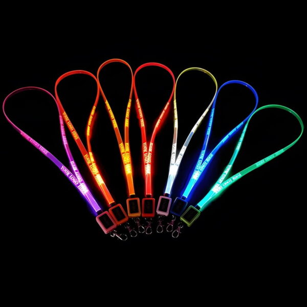 Seven LED lanyards lined up in a dark room glowing pink, orange, yellow, red, white, blue, and green with custom logo laser engraved onto them