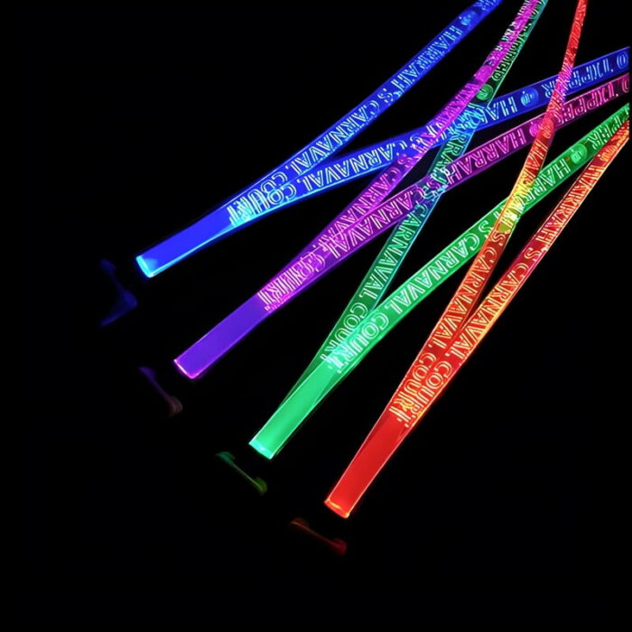 Carnival logo laser engraved onto bright neon LED lanyards shining red, green, purple and blue on four different lanyards in a dark room