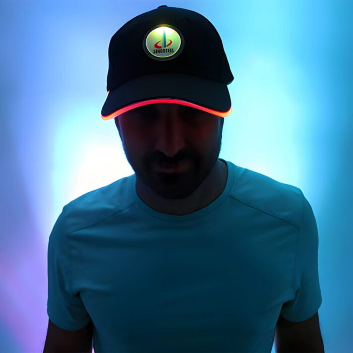 A man in a white illuminated hat featuring a logo, with a red glowing brim, posing for the camera