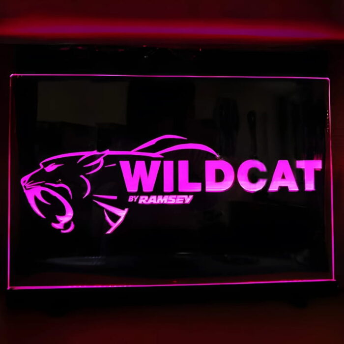 Wildcat text and logo laser engraved onto neon acrylic sign lighting up bright pink in dark room