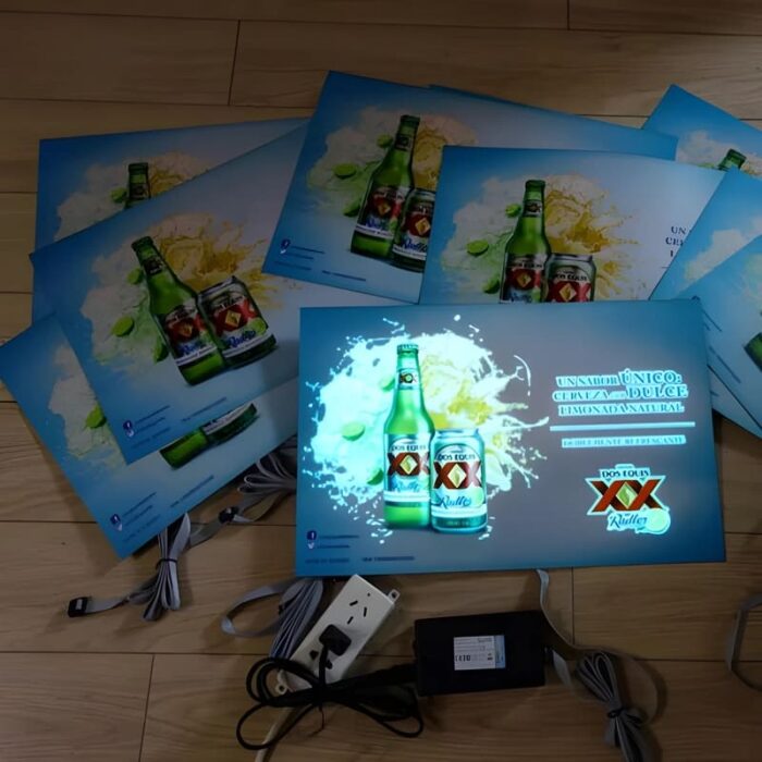 Dos Equis posters in a pile on the floor, one plugged in on the center lighting up brightly