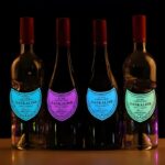 Four wine bottles in a row each with their own brightly lit up neon EL panel label