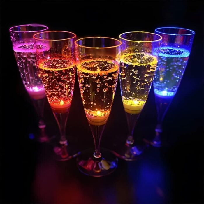 Five different color LED Champagne flutes in a V pattern brightly glowing in dark room