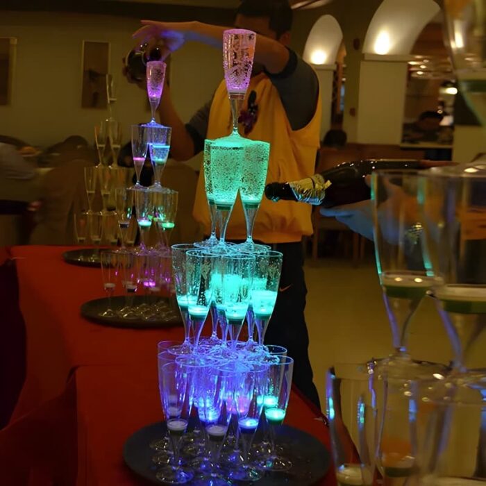 LED champagne glasses stacked into a tower glowing bright neon blue and green at wedding