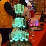 Three tiers of LED champagne glasses stacked up high on a table illuminating bright green