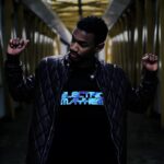 Man holding up two fists in hall way while wearing light up t-shirt that glows with battery pack