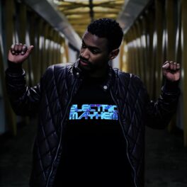 Man holding up two fists in hall way while wearing light up t-shirt that glows with battery pack