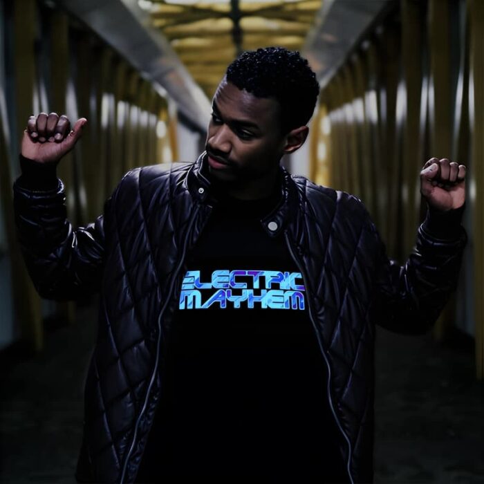 Man holding up two fists in hall way while wearing light up t-shirt that glows with battery pack