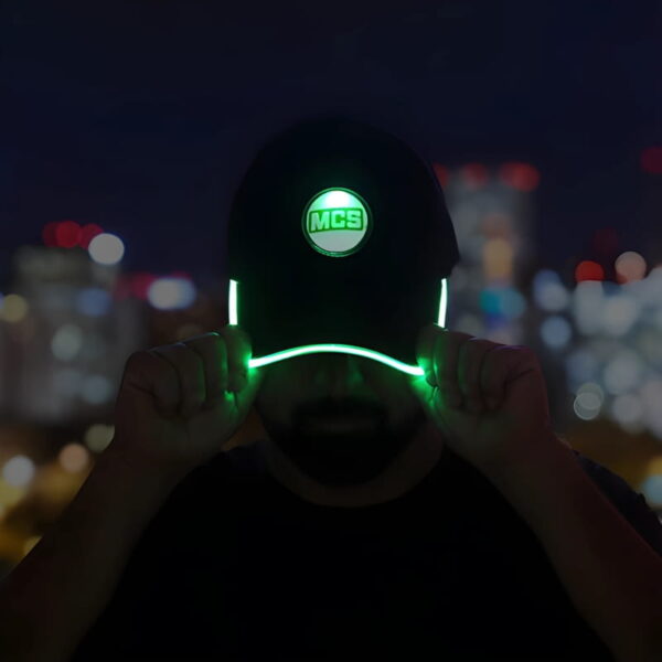 A man in a green hat featuring a glowing logo, with the brim brightly lit in green.