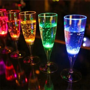 Five LED champagne glasses lighting up bright rainbow colors, with blue and green in the foreground and yellow orange and red in the background illuminating brightly on dark bar