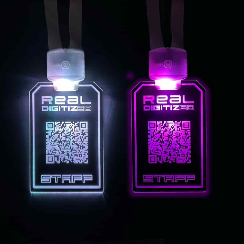 Two light up badges lighting up in white and pink for staff to wear at an event