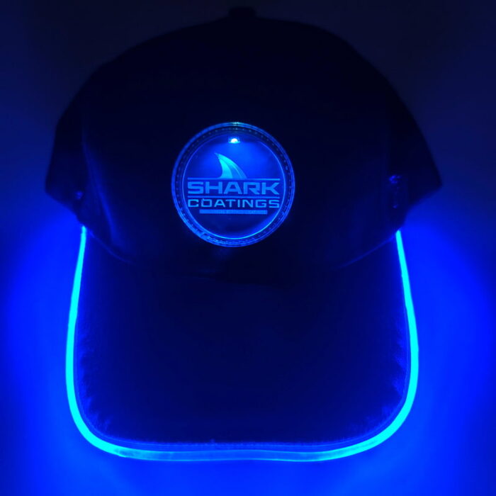 A stylish black hat with a bright blue illuminated logo, perfect for nighttime wear.