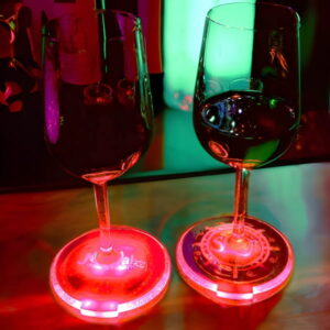 Two wine glasses on bar sitting on customized LED coasters