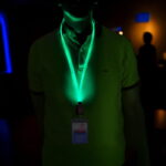 A man with a glowing green lanyard and ID badge, illuminated for visibility at a conference event