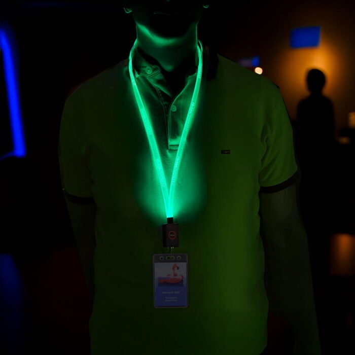A man with a glowing green lanyard and ID badge, illuminated for visibility at a conference event