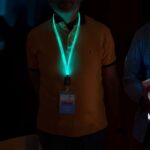 Two men sporting illuminated, branded lanyards that glow in the dark, enhancing their appearance in a low-light environment