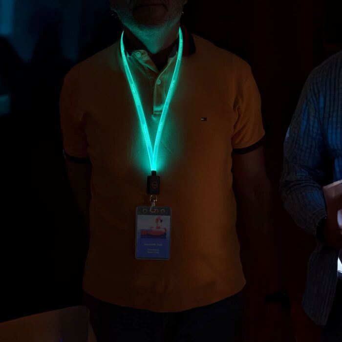 Two men sporting illuminated, branded lanyards that glow in the dark, enhancing their appearance in a low-light environment