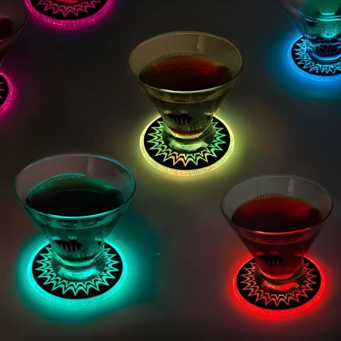 Four glasses on light-up coasters, glowing in green, red, and yellow LED lights