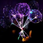 A person holds a colorful bunch of illuminated balloons