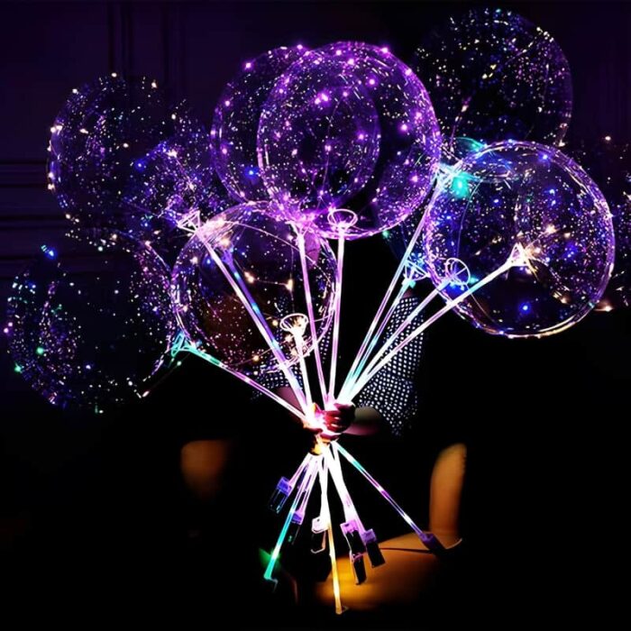 A person holds a colorful bunch of illuminated balloons