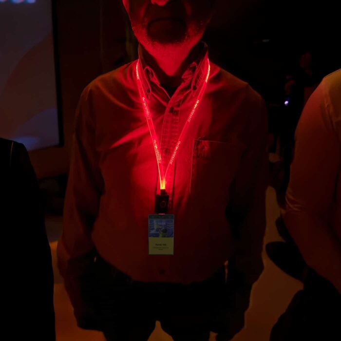 A man at a conference wearing a red LED lanyard that illuminates a custom logo