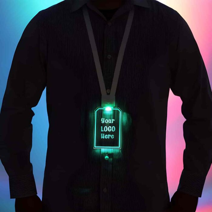 Silhouette of man in button down shirt from the neck down wearing a glowing LED ID badge around their neck which shines bright green in a dark setting