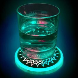 Picture of glass of water on LED drink coaster which is glowing bright green and making the drink glow as well
