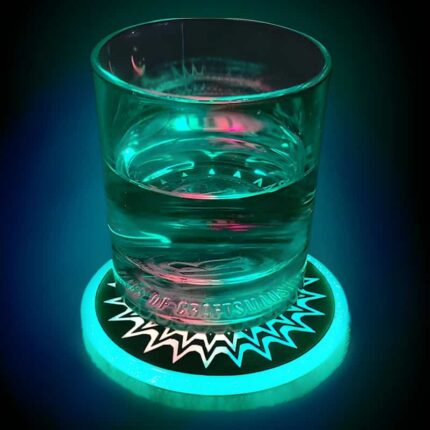 Picture of glass of water on LED drink coaster which is glowing bright green and making the drink glow as well