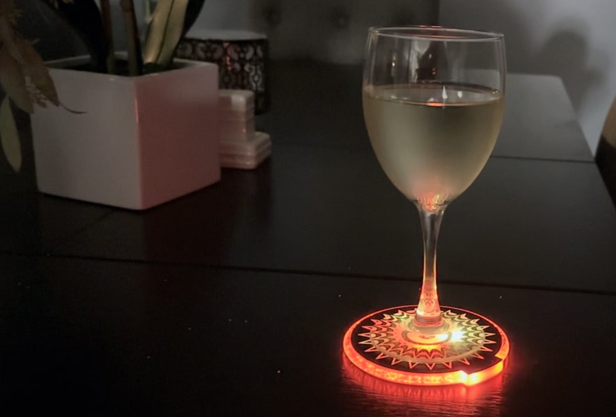 A glass of wine on a color-changing coaster glowing orange, adding a vibrant touch to the setting