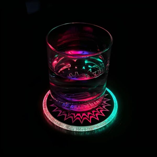 A glass of water illuminated by a colorful light from a light-up drink coaster beneath it