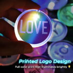 Someone holding a custom Love Wins political LED pin in front of other LED pin designs in the background