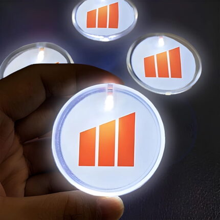 Close up of hand holding an LED pin with logo design glowing brightly