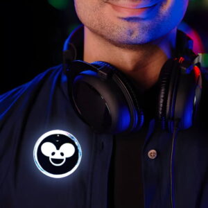 Close up of man wearing big headphones around their neck with a custom DJ inspired LED pin on his jacket, lighting up bright white