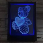A 3D printed teddy bear with a heart, illuminated within a picture frame, showcasing its charming design.