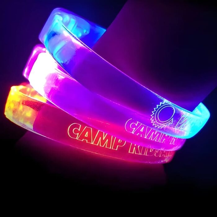 Three custom LED bracelets on wrist each lighting up a different neon color: orange, pink and blue