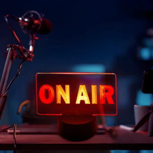 On Air red led sign lighting up on desk of podcast set