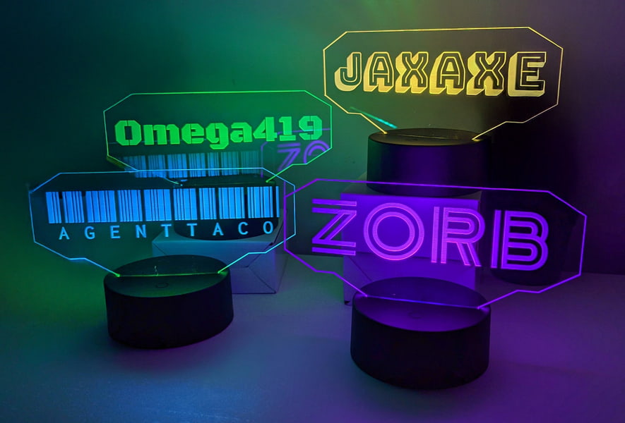 Four acrylic LED table lamps in various colors, featuring the names Omega, Jaxx, and Zorba, glowing softly