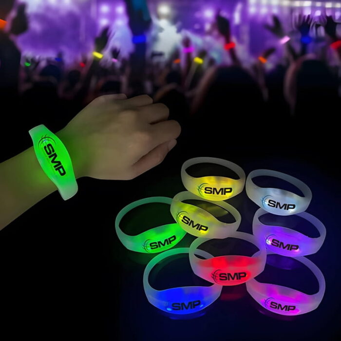 Close up of wrist wearing customized led bracelet in front of crowd waving light up wristbands