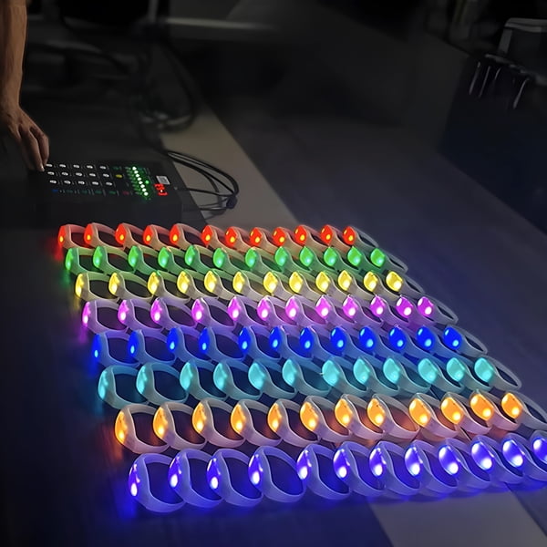 Large table with LED bracelets lined up in 8 different zones next to remote controller to wirelessly synchronize