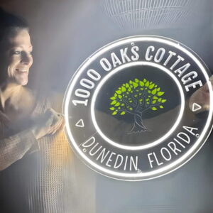 Smiling woman holding custom LED neon sign with business logo and location brightly