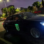A black car featuring a light-up "EL" sticker panel with the Monster logo attached