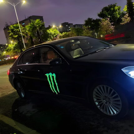 A black car featuring a light-up "EL" sticker panel with the Monster logo attached