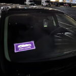 ride share glowing logo el car sticker lighting up on front windshield of car