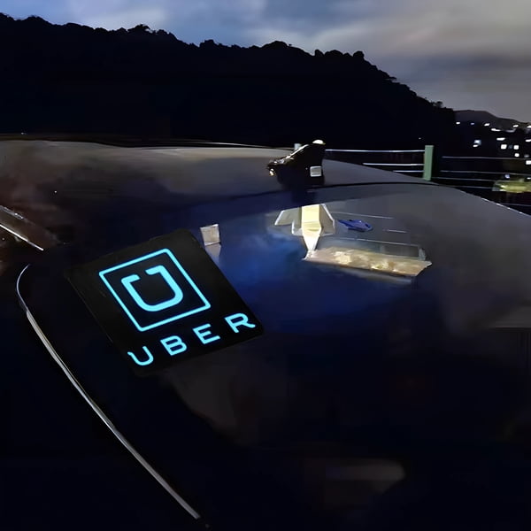 uber logo illuminating brightly on back windshield of car at dusk
