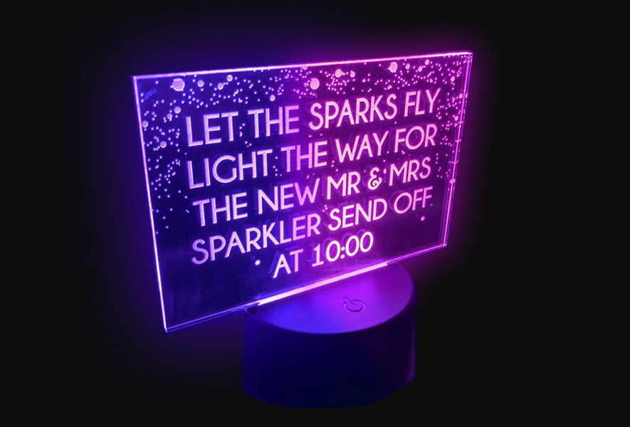 Acrylic LED table lamp with dual colors, featuring the phrase "Let the sparks fly" illuminated in vibrant light