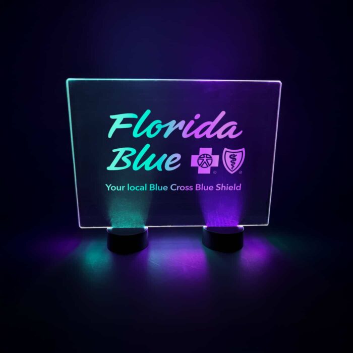 A custom engraved led table sign for Florida Blue Cross Blue Shield event glowing in green and purple neon glow