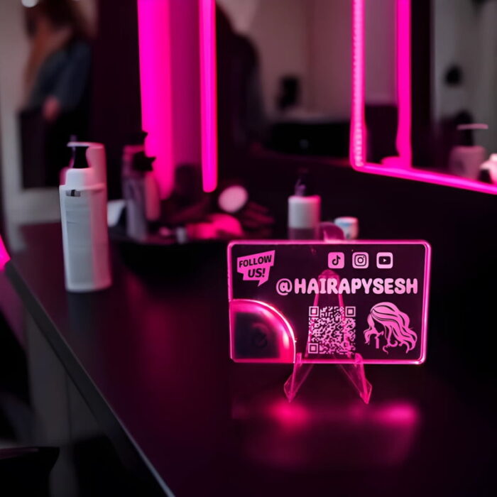 A pink illuminated acrylic business card displayed in a hair salon business